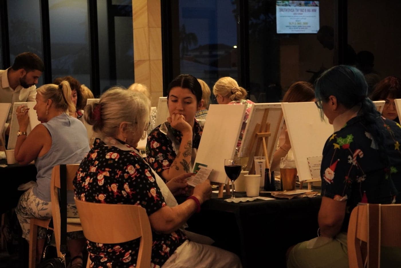 Guests concentrating on their canvases around a table.