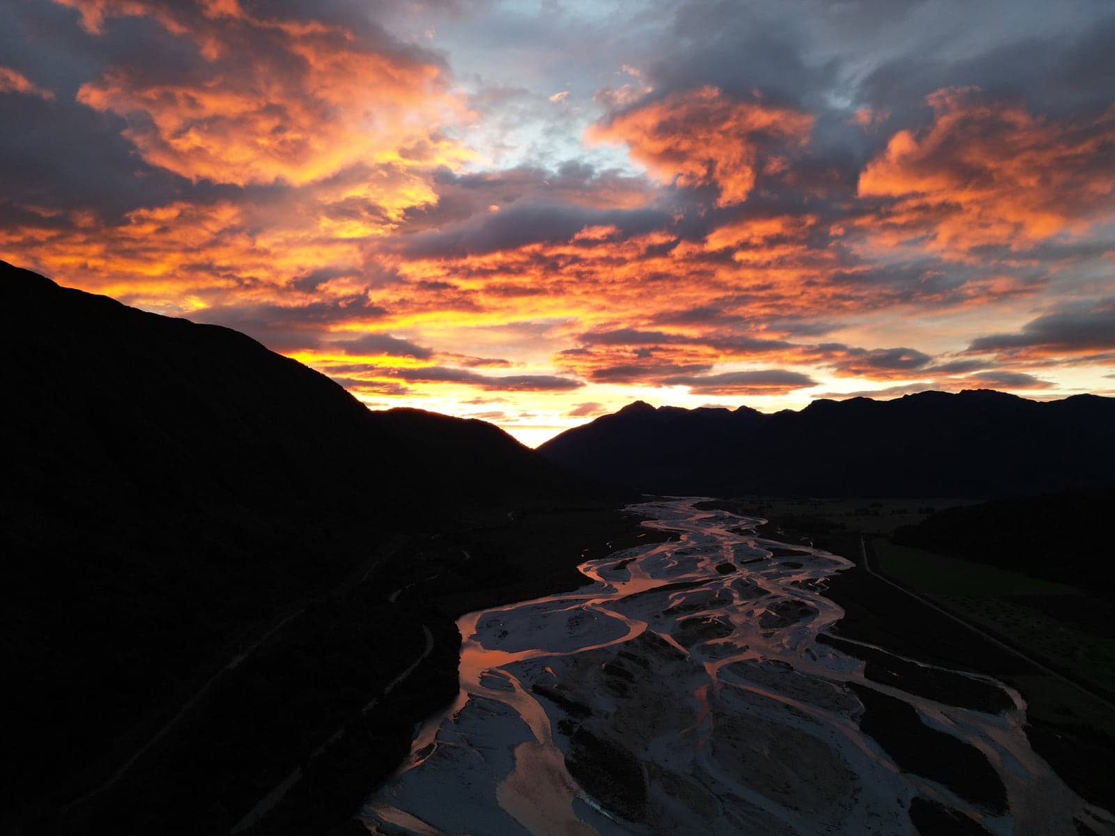 Un río trenzado bajo un cielo encendido al atardecer, Isla Sur, Nueva Zelanda.