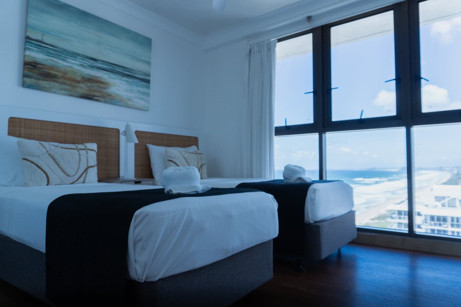 Un dormitorio con dos camas y una pared de ventanas que mira a la playa — Boulevard North.