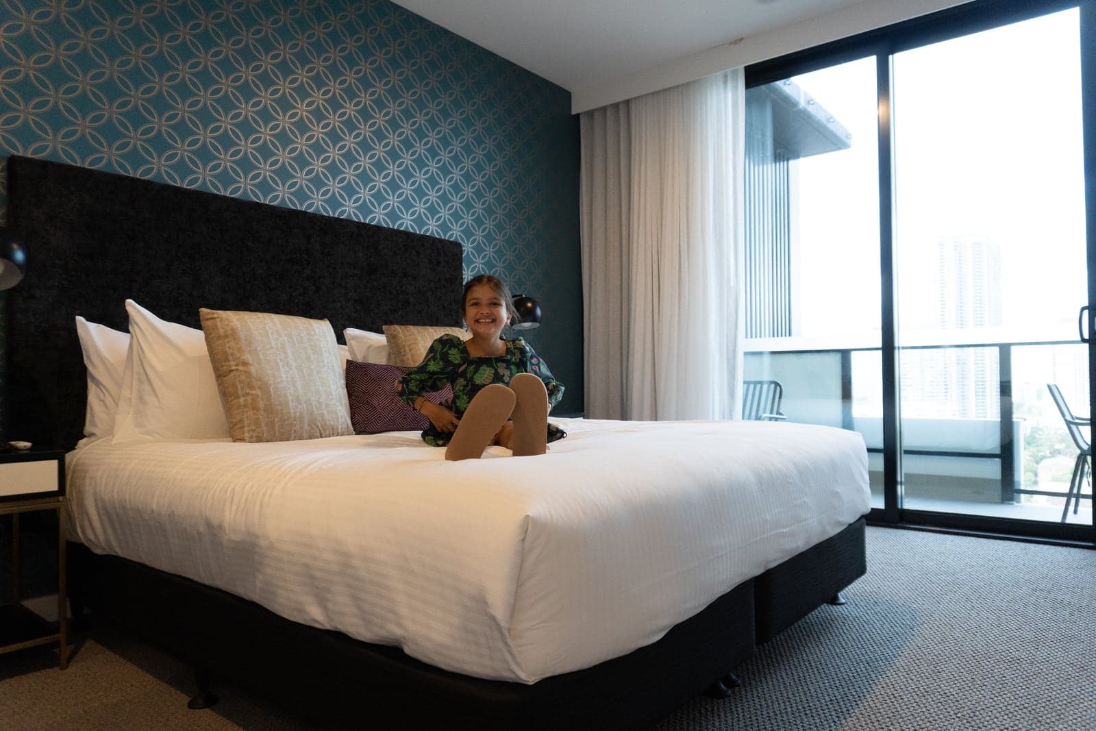Una huésped en una cama king junto a ventanales de piso a techo, TRYP Southport.