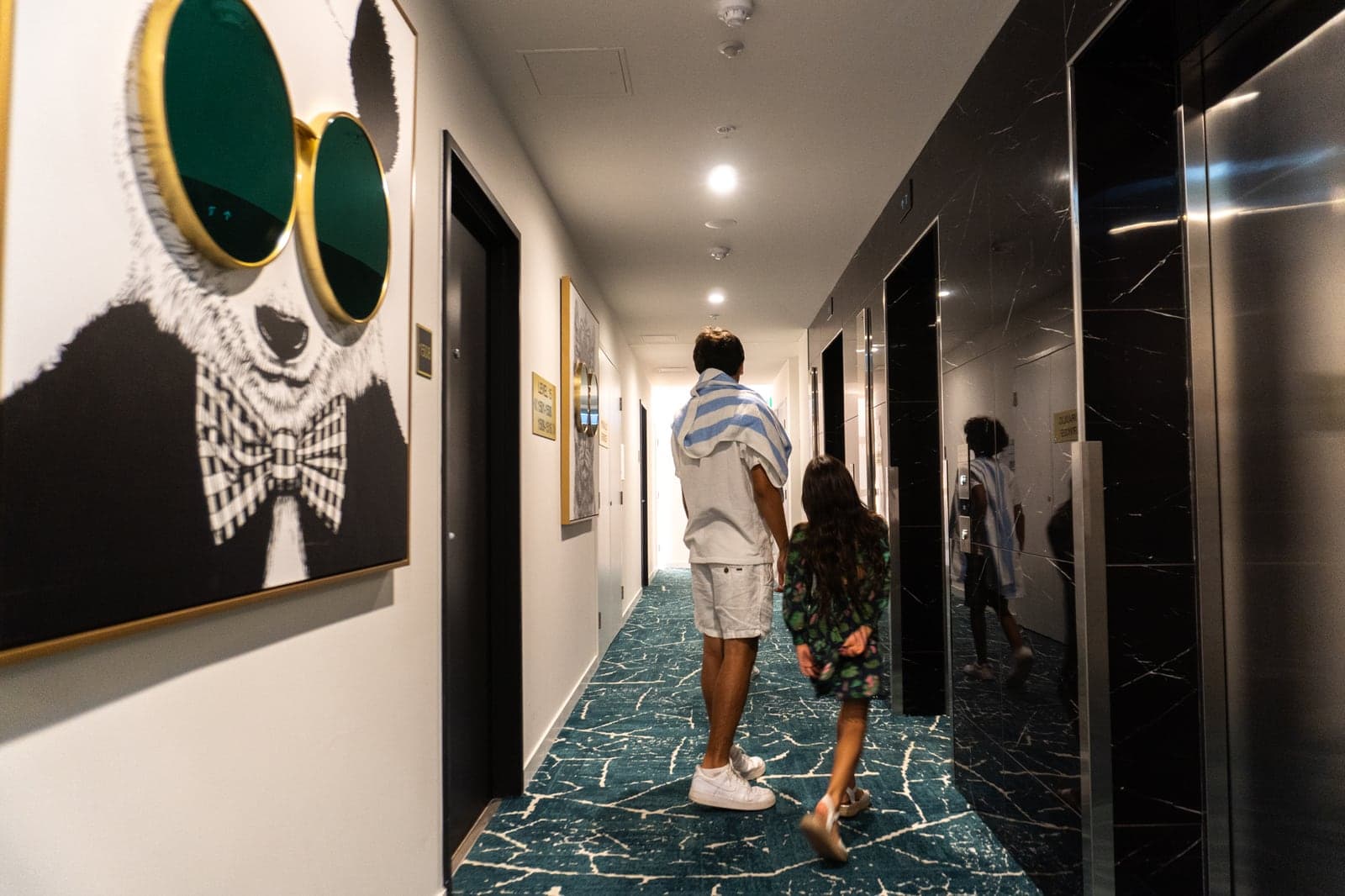 Huéspedes caminando por un pasillo del TRYP, junto a una obra de gran formato.