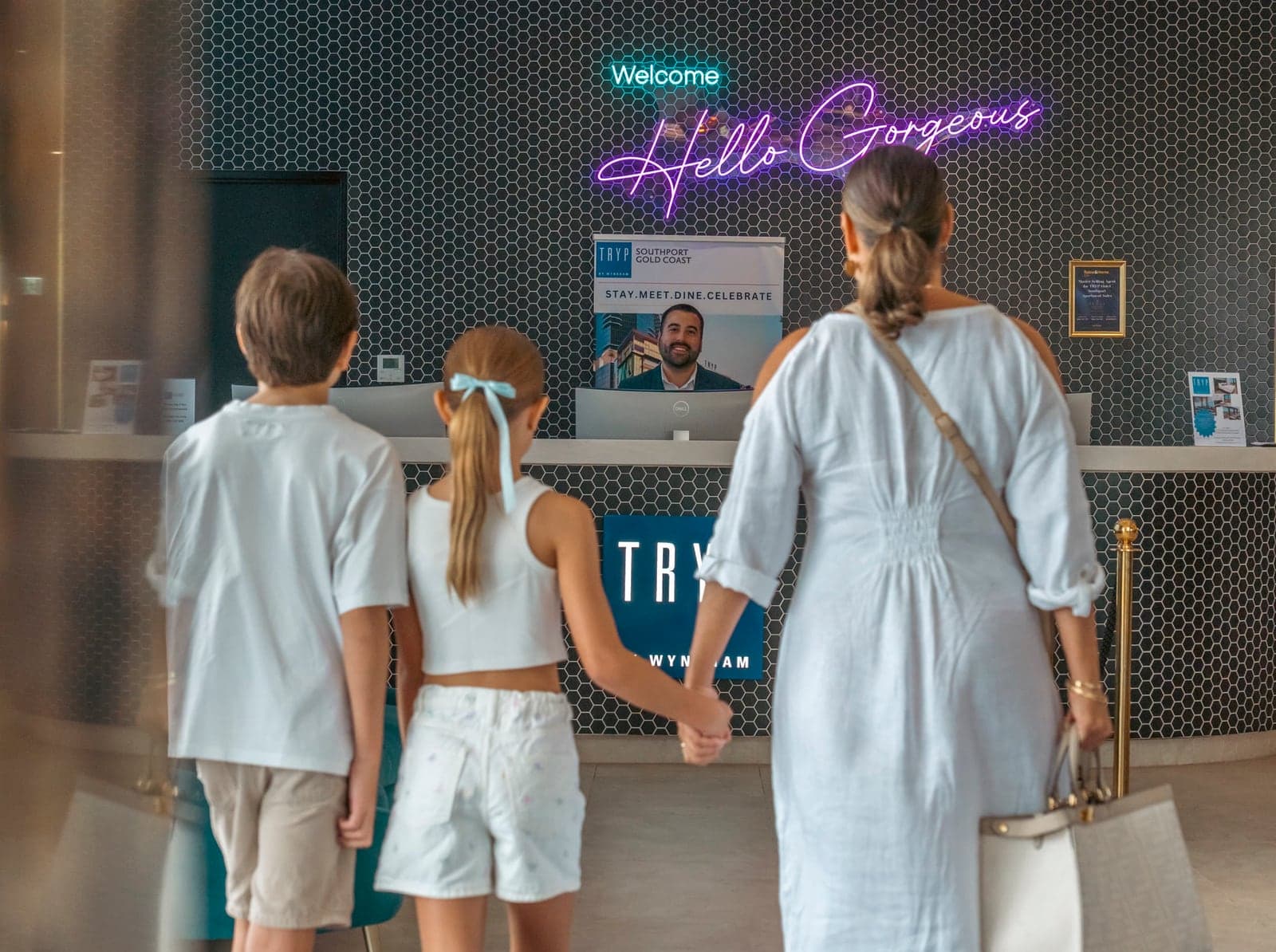 Una madre y sus dos hijos caminan de la mano hacia la recepción de TRYP by Wyndham Southport.